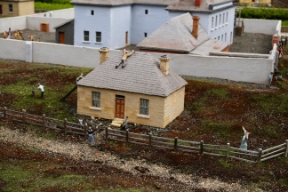 Een huisje met op de achtergrond de gevangenis van Old Hobart Town